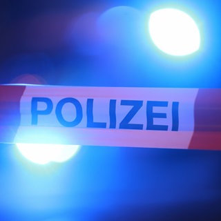 Blaulichter leuchten hinter einem Absperrband der Polizei. In Filderstadt-Bonlanden hat ein Bauhof-Mitarbeiter die Leiche eines Menschen gefunden.