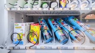 Lachgas-Flaschen in einem Verkaufsautomaten, sie sind mit dem Preis von 20 Euro pro Dose gekennzeichnet (Archivbild)