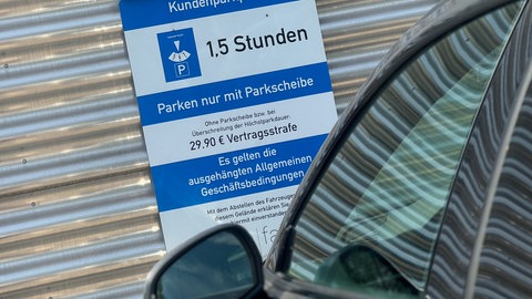 Ein Schild auf einem Kundenparkplatz mit dem Hinweis "Parken nur mit Parkscheibe für die Dauer des Einkaufs"