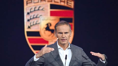 Oliver Blume, Vorstandsvorsitzender der Porsche AG - und der Volkswagen AG, bei einem Vortrag vor dem Porsche-Logo.