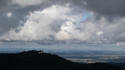 Dunkle Wolken sind über der Burg Teck am Rand der Schwäbischen Alb zu sehen. Nach Gewitter am Freitag werden in BW am Wochenende spätsommerliche Temperaturen erwartet. (Symbolbild)