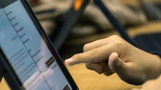 Symbolbild | Die Hand eines Jungen tippt auf einem Tablet. Auch den Umgang mit KI-Chatbots sollen Schulen vermitteln: Kinder sollen mit dem speziell für sie entwickelten Chatbot, dessen server in Europa ist, den verantwortungsvollen Umgang mit KI lernen.