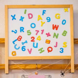 Eine Tafel mit Buchstaben und Zahlen in einer Kita. Kinder aus von Armut betroffenen Familien haben seltener einen Kita-Platz.