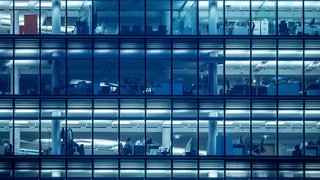 Wenige Menschen arbeiten am späten Nachmittag in einem Bürogebäude.