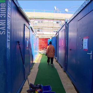 Eine Frau läuft zwischen Containertoiletten hindurch