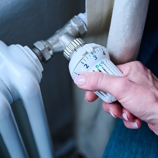 Heizung: Die Hand einer Frau stellt die Temperatur an einem Regler ein.