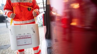 Ein Mitarbeiter des DRK stellt eine Kühlbox für eine Organspende in einen Transporter des Deutschen Roten Kreuzes. (gestellte Szene)
