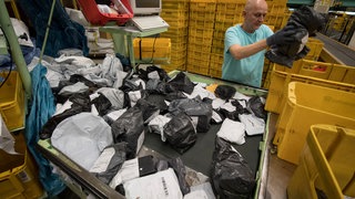 Warensendungen sortiert ein Mitarbeiter im Internationalen Postzentrum (IPZ) am Flughafen in Frankfurt am Main. Täglich kommen hier allein aus dem asiatischen Raum mehrere hunderttausend Sendungen an, werden sortiert und für die Zustellung vorbereitet. 