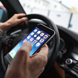 Eine Person bedient das Handy während der Autofahrt. In BW findet die Polizei-Kontrollwoche statt, bis Sonntag kontrollieren die Beamten verschärft, ob Autofahrer am Steuer technische Geräte nutzen.