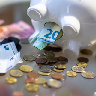 Geld wird aus dem Bauch eines Sparschweins entnommen. Ein Symbol für die Einigung der grün-schwarzen Landesregierung auf einen Nachtragshaushalt.