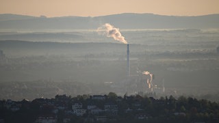Dampf bildet im Morgendunst eine Wolke aus einem Schornstein eines Kraftwerks.