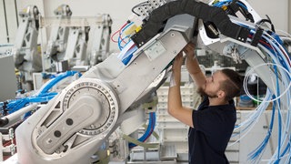 Ein Mitarbeiter der Dürr AG montiert einen Lackierroboter.