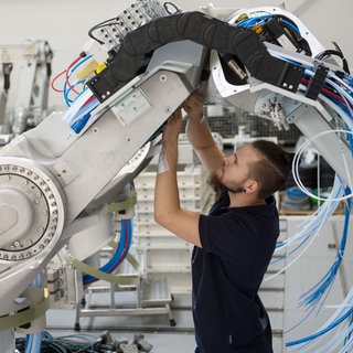 Ein Mitarbeiter der Dürr AG montiert einen Lackierroboter.