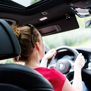 Eine Frau sitzt am Steuer eines Autos. Um einen Führerschein zu bekommen, müssen die Menschen immer mehr Geld bezahlen. Die Politik will gegen die Preis-Steigerungen angehen. Doch oft hängen die hohen Kosten mit den Prüflingen zusammen, die mehr Fahrstunden brauchen und häufiger durchfallen.