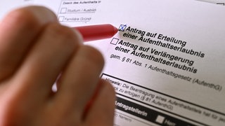 Mann füllt Formular "Antrag auf Erteilung einer Aufenthaltserlaubnis" aus