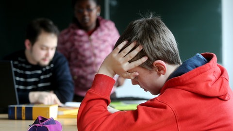 Ein Junge in einem Klassenzimmer stützt seinen Kopf auf einem Tisch ab. Immer mehr Schüler leiden an psychischen Störungen wie Autimus oder Erkrankungen wie Depression.
