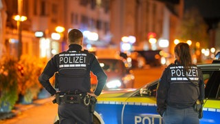 Zwei Polizisten stehen bei ihrem Streifenwagen am Straßenrand. An Halloween kam es im Land zu einigen Zwischenfällen.