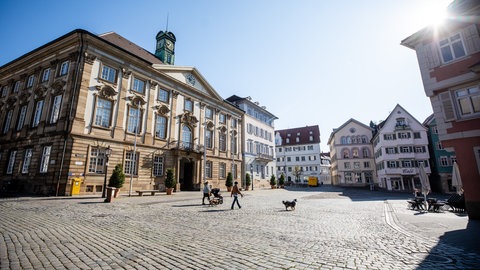 Nur wenige Menschen gehen bei schönem Wetter über den Rathausplatz in Esslingen.