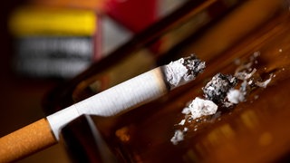 Eine brennende Zigarette liegt in einem Aschenbecher. Der Nichtraucherschutz in Baden-Württemberg soll verschräft werden.