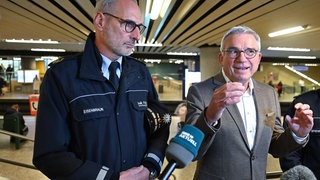 Thomas Strobl (r, CDU), Innenminister von Baden-Württemberg, spricht an der Straßenbahnhaltestelle Charlottenplatz nach Kontrollen in der Messerverbotszone mit Journalisten. Links steht Markus Eisenbraun, Präsident des Polizeipräsidiums Stuttgart.