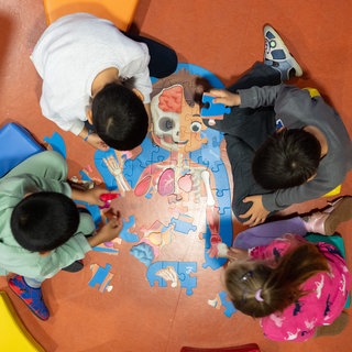Kinder legen am Rande einer Pressekonferenz in einer Kindertagesstätte ein Puzzle zusammen.