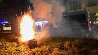 Silvesterfeuerwerk explodiert während der Silvesternacht in Neukölln vor einem Polizeiauto.