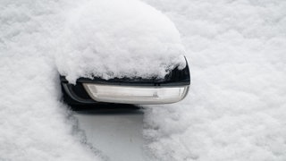 Der Außenspiegel eines Autos ist mit Schnee bedeckt. Am Samstag rechnet der DWD mit Schnee in weiten Teilen von Baden-Württemberg.