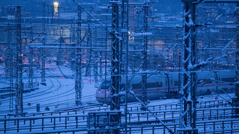 Ein Zug fährt über das verschneite Gleisvorfeld des Stuttgarter Hauptbahnhofs.