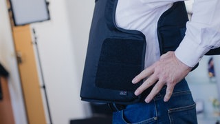 Ein Gerichtsvollzieher zieht bei einem Pressetermin eine Schutzweste an (Archivbild aus NRW)