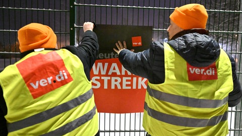 Streik im kommunalen Nahverkehr: Streikende hängen ein Plakat von ver.di auf.