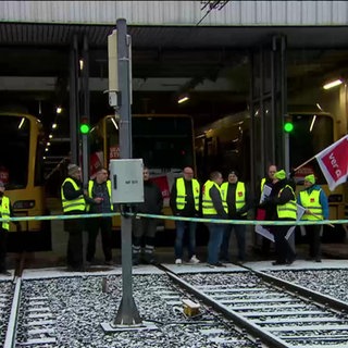 Mitglieder der Gewerkschaft ver.di stehen an einem Bahnhof