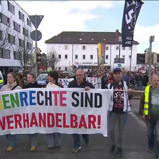 Demonstranten gegen Rechts halten einen großen Banner mit der Aufschrift: "Menschenrechte sind nicht verhandelbar!"