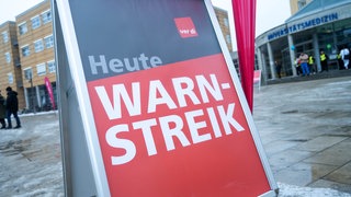 Ein Schild mit der Aufschrift "Warnstreik" steht vor dem Gebäude der Universitätsmedizin in Greifswald.