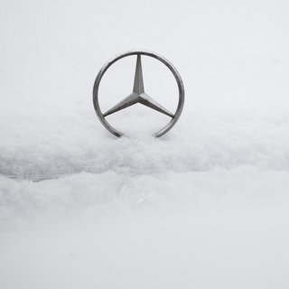 Ein Mercedes-Stern auf der schneebedeckten Motorhaube eines Autos