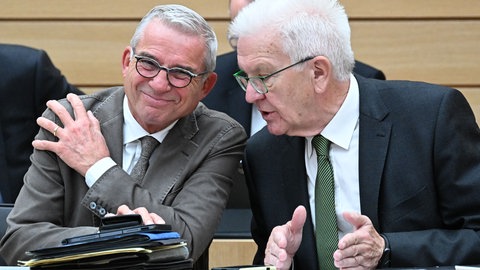 Thomas Strobl (l, CDU), Innenminister von Baden-Württemberg, und Winfried Kretschmann (Bündnis 90Die Grünen), Ministerpräsident von Baden-Württemberg, unterhalten sich im Landtag.