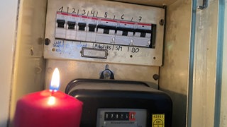 Kerze beleuchtet alten Stromzähler in einem Kasten. Ein großflächiger Stromausfall legte den Schwarzwald-Baar-Kreis lahm. In der Region Stuttgart und in Tübingen gab auch Stromausfälle. Wird es mehr?