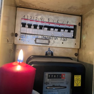 Kerze beleuchtet alten Stromzähler in einem Kasten. Ein großflächiger Stromausfall legte den Schwarzwald-Baar-Kreis lahm. In der Region Stuttgart und in Tübingen gab auch Stromausfälle. Wird es mehr?