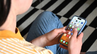 Eine Jugendliche sitzt auf dem Boden und nutzt ein Smartphone - auf dem Display sind verschiedene Apps zu sehen. Die Debatte um ein Social-Media-Verbot für Kinder und Jugendliche hat wieder Fahrt aufgenommen.