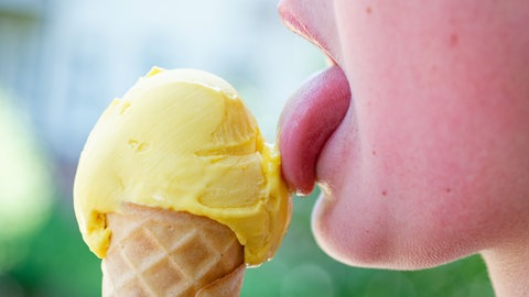 Ein Junge schleckt an einer Kugel Eis in einer Waffel. In einigen Eisdielen in BW sind die Eispreise 2026 weiter gestiegen.
