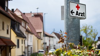 Ein Schild mit der Aufschrift «Arzt» hängt an einer Straßenlaterne. Im baden-württembergischen Landarzt-Programm ist fast jeder zehnte geschaffene Platz nicht mehr mit Studierenden aus dem Programm besetzt. 