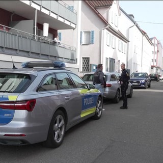 Ein Polizeifahrzeug und mehrere Einsatzkräfte stehen in einer Wohnstraße