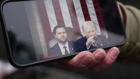 Trump auf dem Handy in typischer machtpose mit ausgestrecktem Finger