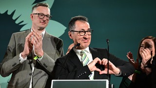 Grüne-Spitzenkandidat Cem Özdemir (Mitte) Fraktionsvorsitzender Andreas Schwarz stehen bei der Wahlparty der Grünen auf der Bühne.