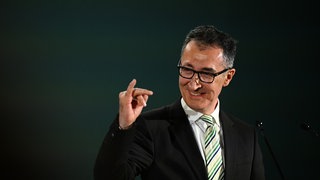 Cem Özdemir (Grüne), Spitzenkandidat Landtagswahl Baden-Württemberg, macht bei der Wahlparty seiner Partei eine Geste und reckt den kleinen Finger der rechten Hand hoch.