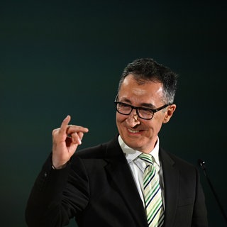 Cem Özdemir (Grüne), Spitzenkandidat Landtagswahl Baden-Württemberg, macht bei der Wahlparty seiner Partei eine Geste und reckt den kleinen Finger der rechten Hand hoch.