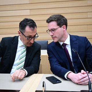 Cem Özdemir und Manuel Hagel sitzen bei einer Pressekonferenz auf der Regierungsbank im Plenarsaal des Landtags und neigen die Köpfe zueinander. Nach der Landtagswahl stehen die Koalitionsverhandlungen von Grünen und CDU bevor.
