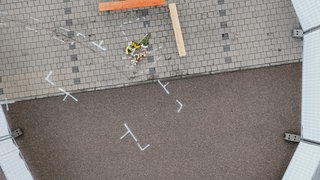 Der Parkplatz eines Supermarktes in Niedernhall, auf dem Blumen liegen und ein Bereich abgesperrt ist (Aufnahme mit einer Drohne)