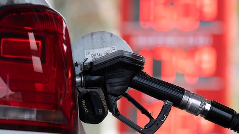Ein Tankstutzen steckt an einer Tankstelle in der Tanköffnung eines Fahrzeugs. Bund will Ölreserven freigeben und Spritpreis-Anstieg bremsen.