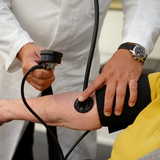 Ein Hausarzt misst in seiner Praxis in Stuttgart einer Patientin den Blutdruck.