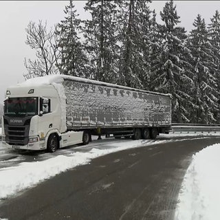 Ein LKW steht auf einer verschneiten Straße.